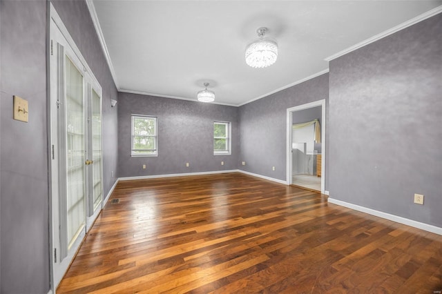 empty room with crown molding, baseboards, a chandelier, and hardwood / wood-style floors