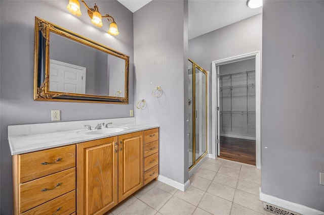 bathroom featuring vanity, tile patterned floors, baseboards, and a stall shower