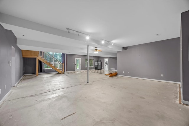 below grade area featuring stairs, ceiling fan, track lighting, and baseboards