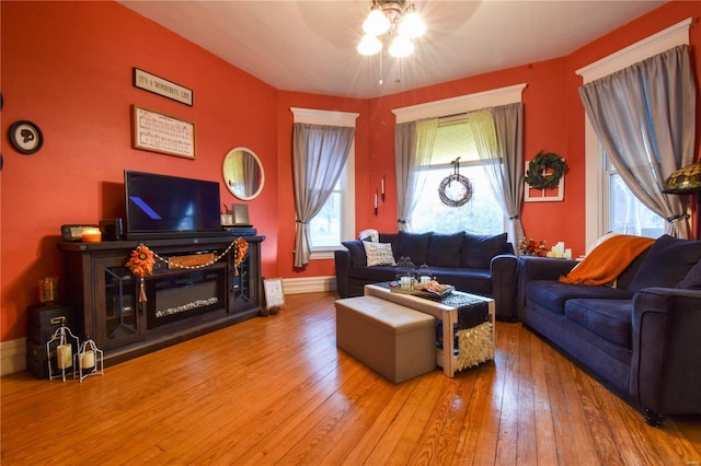 living room with wood-type flooring, a ceiling fan, baseboards, and plenty of natural light