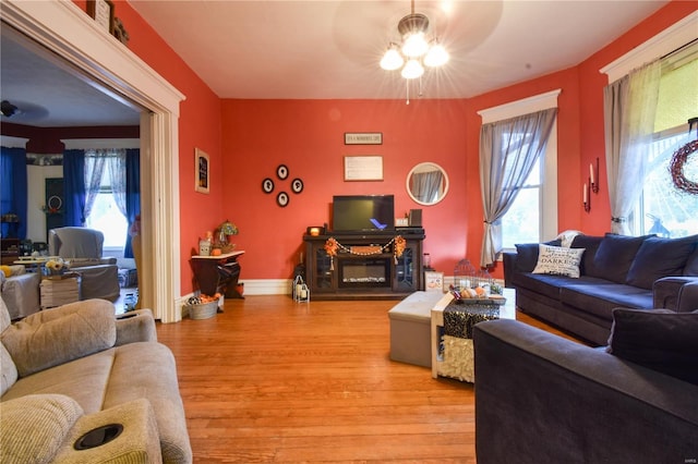 living area featuring light wood finished floors, ceiling fan, and a healthy amount of sunlight