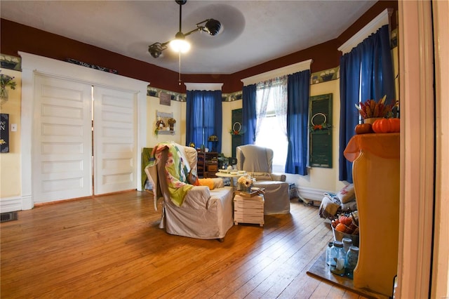 living area featuring wood-type flooring, a ceiling fan, and visible vents