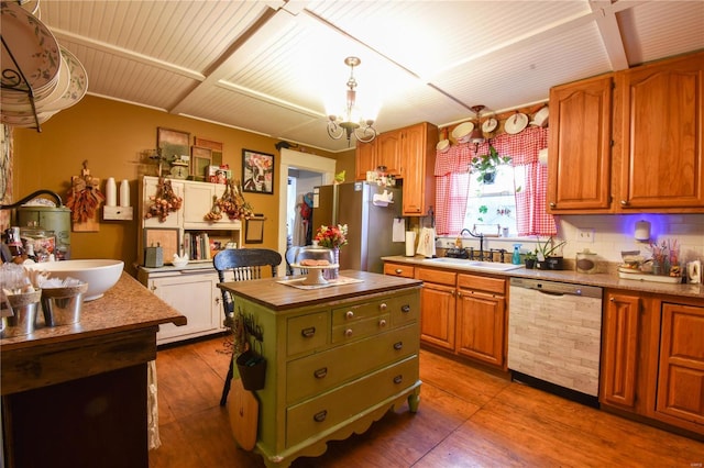 kitchen with freestanding refrigerator, decorative backsplash, wood finished floors, dishwashing machine, and a sink