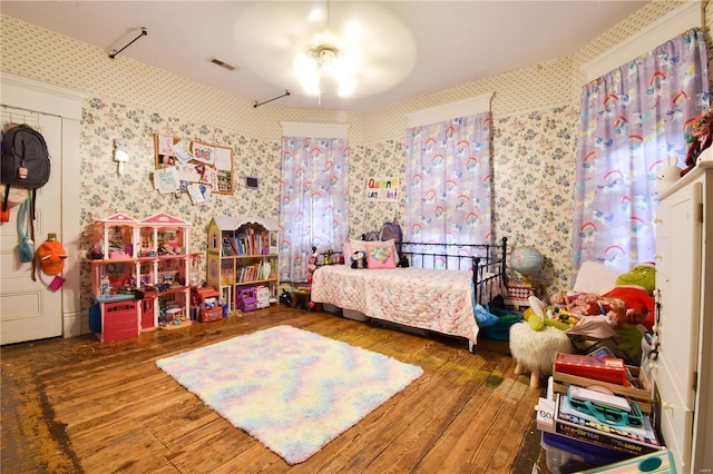 bedroom with wallpapered walls, hardwood / wood-style flooring, and visible vents