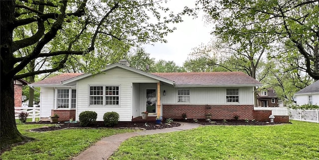 ranch-style house with brick siding, fence, a chimney, and a front lawn