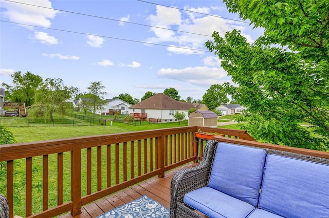 wooden deck featuring a storage shed, an outdoor structure, a residential view, a fenced backyard, and a lawn