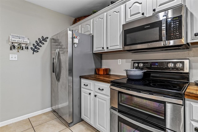 kitchen featuring wood counters, white cabinets, appliances with stainless steel finishes, and light tile patterned floors