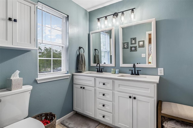 bathroom with a sink, double vanity, toilet, and baseboards