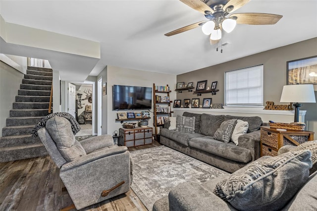living area featuring stairway, a ceiling fan, and wood finished floors