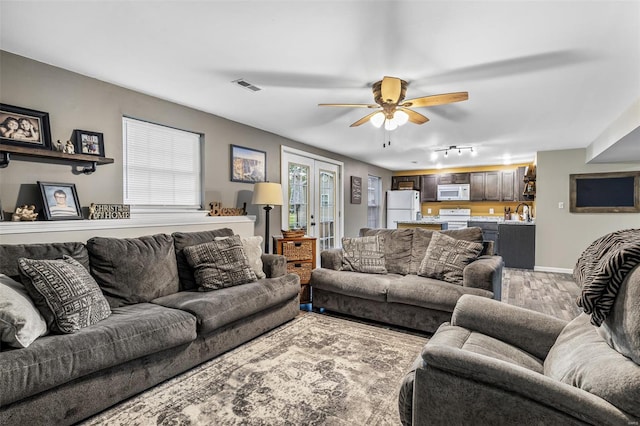 living room with french doors, light wood-style flooring, ceiling fan, visible vents, and track lighting