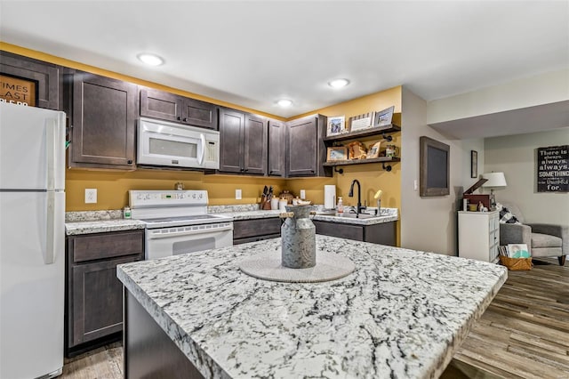 kitchen with dark brown cabinets, white appliances, a sink, open shelves, and wood finished floors