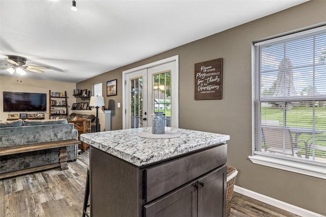 kitchen featuring french doors, dark wood finished floors, ceiling fan, light countertops, and a kitchen island
