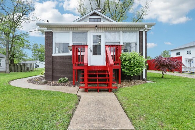 view of front of home featuring brick siding, a front lawn, and fence