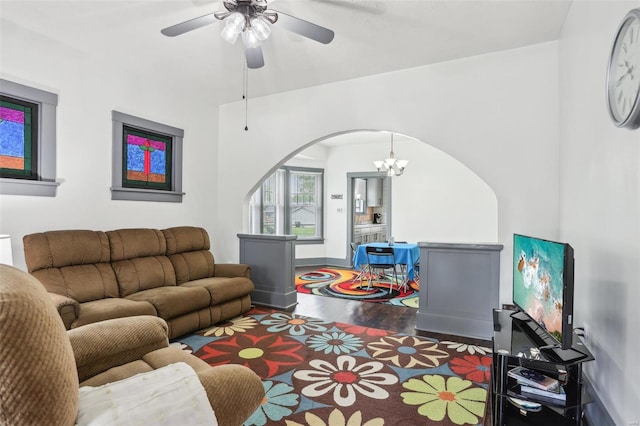 living area with arched walkways, wood finished floors, and ceiling fan with notable chandelier