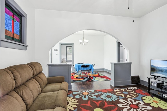 living area with arched walkways, baseboards, a chandelier, and wood finished floors