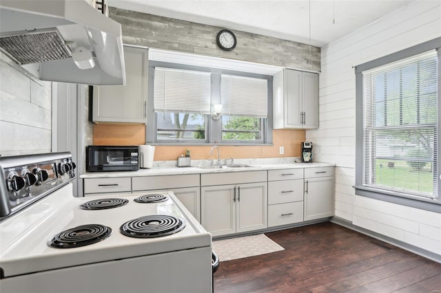 kitchen featuring electric range, a sink, light countertops, under cabinet range hood, and dark wood-style floors
