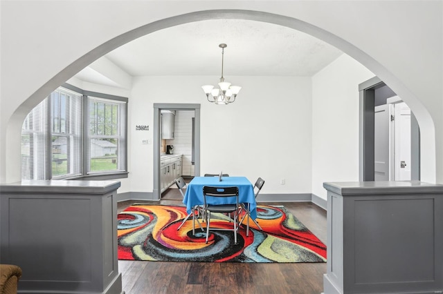 dining space with arched walkways, baseboards, a notable chandelier, and wood finished floors