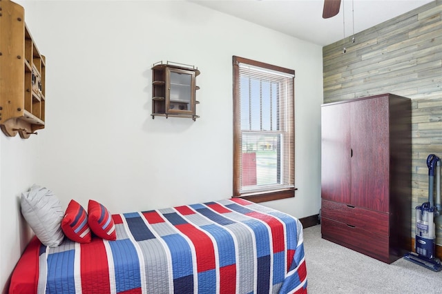 carpeted bedroom with ceiling fan and wood walls