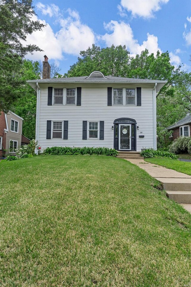 colonial home with a chimney and a front lawn