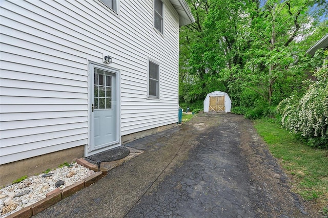 view of property exterior featuring aphalt driveway, an outbuilding, and a storage unit
