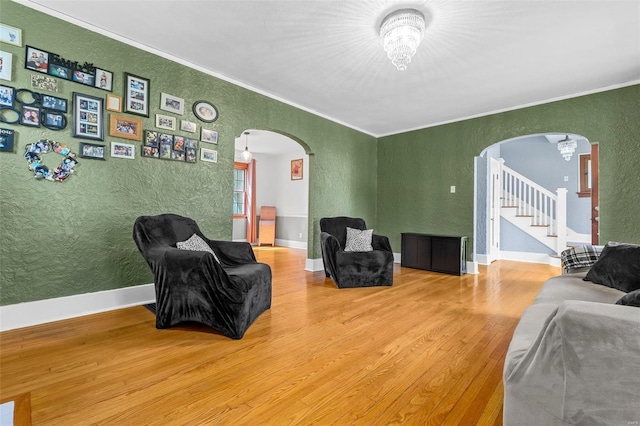 living area with arched walkways, a textured wall, and ornamental molding