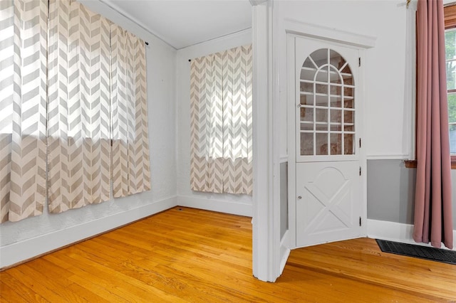 interior space with baseboards, ornamental molding, light wood-style floors, and visible vents