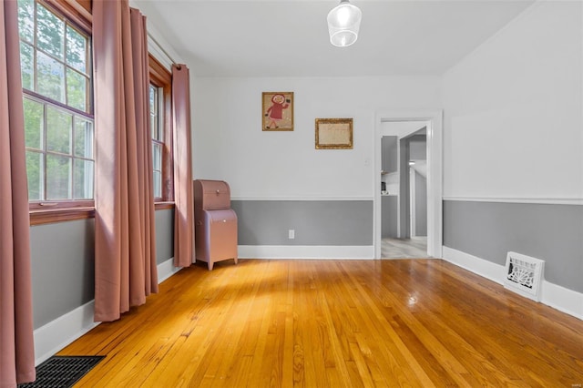 empty room featuring light wood-style floors, baseboards, and visible vents