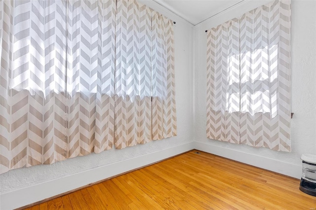 spare room with baseboards, light wood finished floors, and crown molding