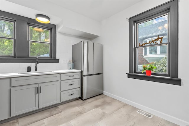 kitchen featuring plenty of natural light, visible vents, a sink, gray cabinetry, and freestanding refrigerator