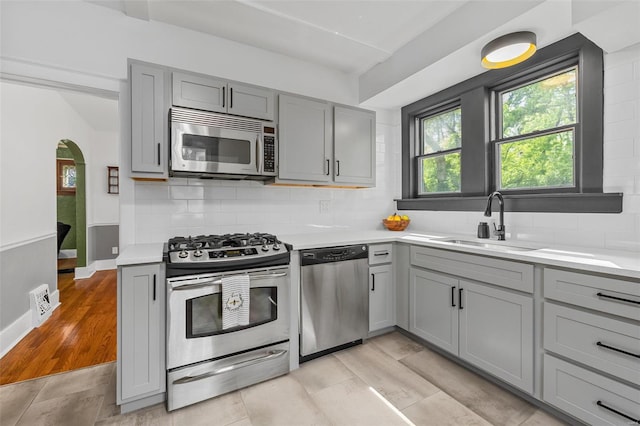 kitchen featuring a sink, light countertops, gray cabinets, and stainless steel appliances