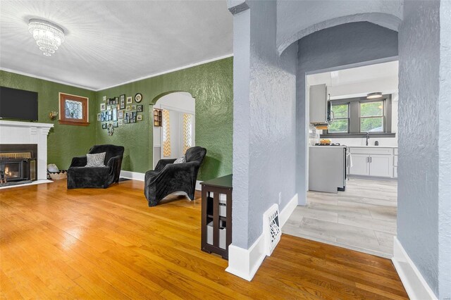 interior space featuring visible vents, a fireplace with flush hearth, arched walkways, a textured wall, and light wood-style flooring