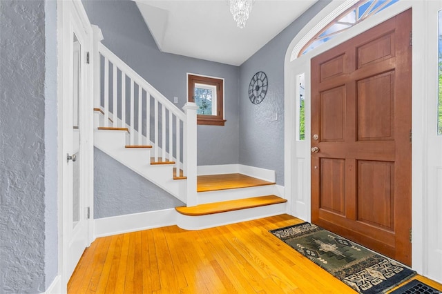 entrance foyer featuring wood-type flooring, stairs, and a textured wall