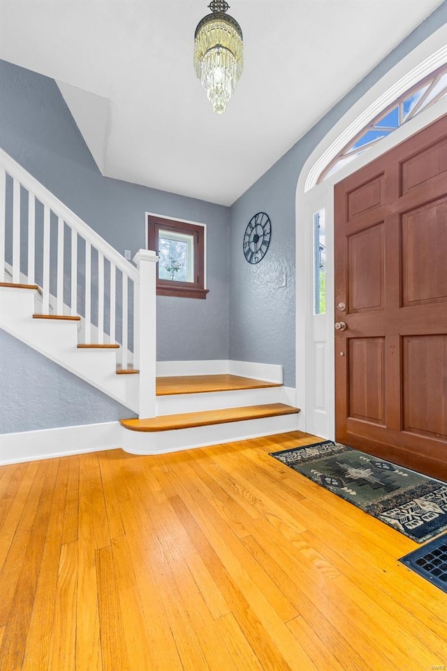foyer entrance featuring an inviting chandelier, baseboards, stairway, and hardwood / wood-style flooring