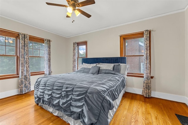 bedroom with baseboards, visible vents, ornamental molding, and light wood finished floors