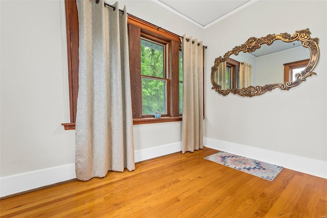 spare room featuring baseboards, crown molding, and wood finished floors