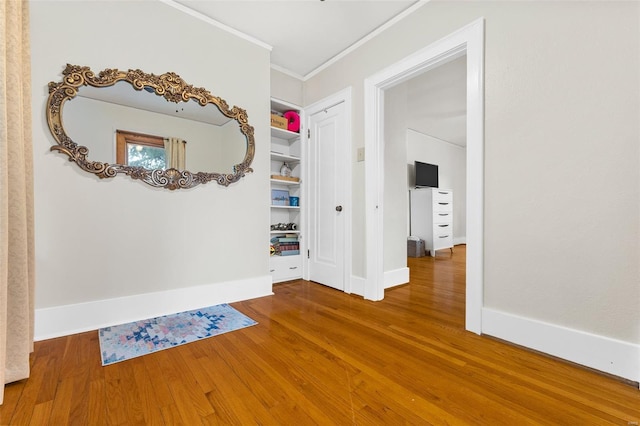 hallway featuring crown molding, baseboards, and wood finished floors