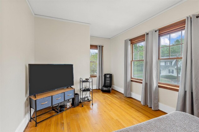bedroom with ornamental molding, light wood finished floors, and multiple windows