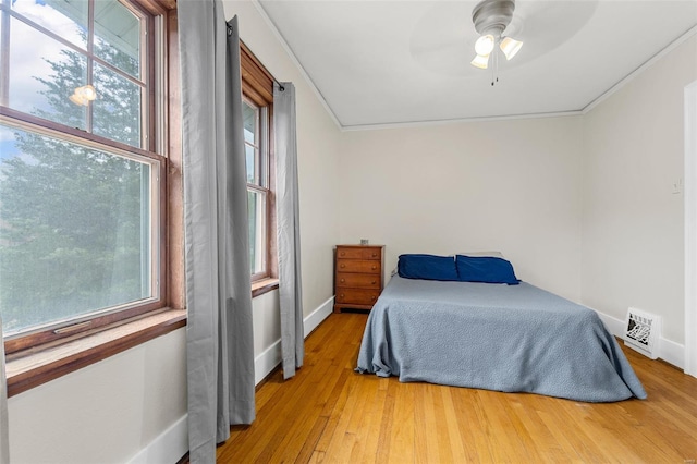 bedroom featuring baseboards, wood finished floors, visible vents, and multiple windows