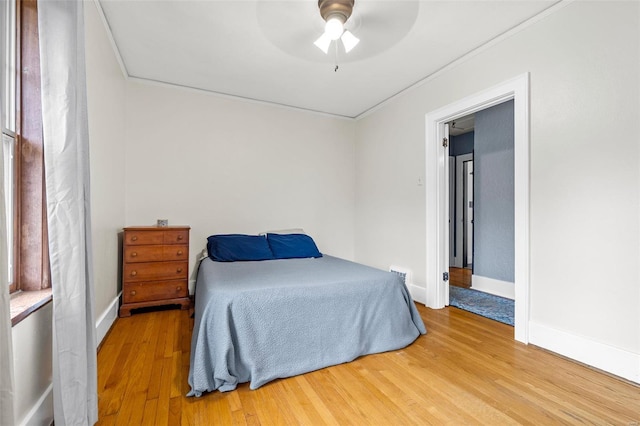 bedroom with baseboards, light wood finished floors, crown molding, and ceiling fan