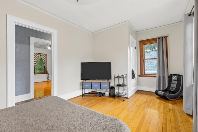 bedroom featuring multiple windows, baseboards, ornamental molding, and light wood finished floors