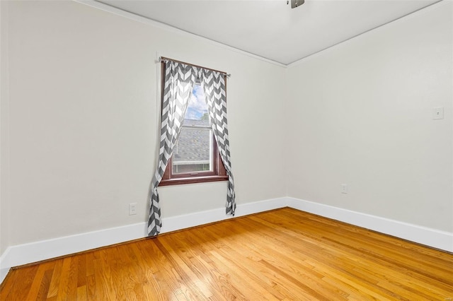 unfurnished room featuring crown molding, baseboards, and light wood finished floors