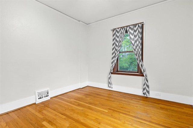 unfurnished room featuring baseboards, visible vents, ornamental molding, and wood finished floors