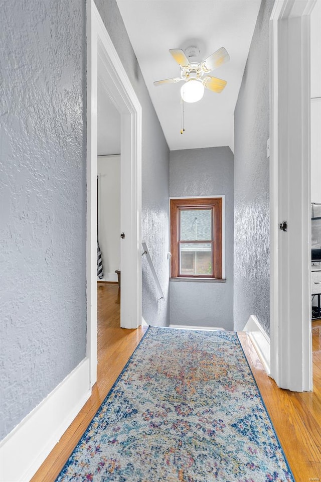 hall with a textured wall and wood finished floors
