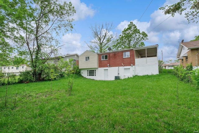 back of house featuring a lawn, central AC unit, and brick siding