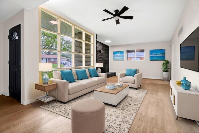 living room with visible vents, light wood-style flooring, ceiling fan, and a wealth of natural light
