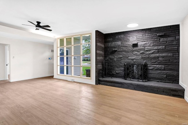 unfurnished living room with baseboards, a ceiling fan, wood finished floors, and a fireplace