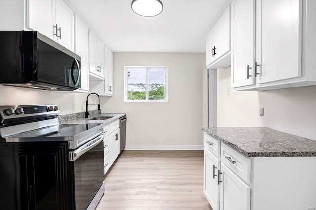 kitchen featuring a sink, light wood finished floors, stainless steel appliances, baseboards, and white cabinetry