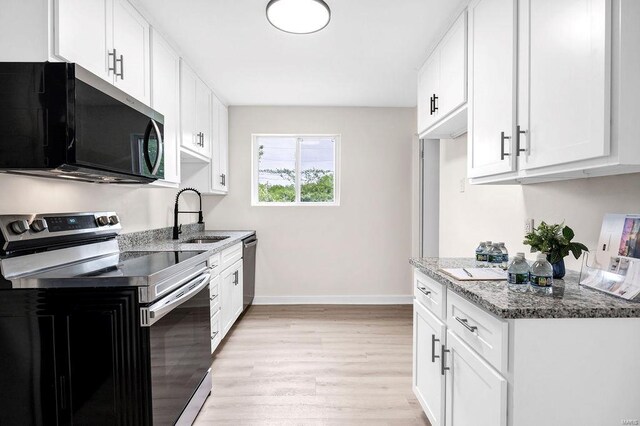 kitchen featuring appliances with stainless steel finishes, a sink, baseboards, stone counters, and light wood-type flooring