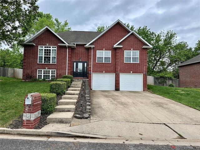 split foyer home featuring fence, brick siding, driveway, a garage, and a front lawn