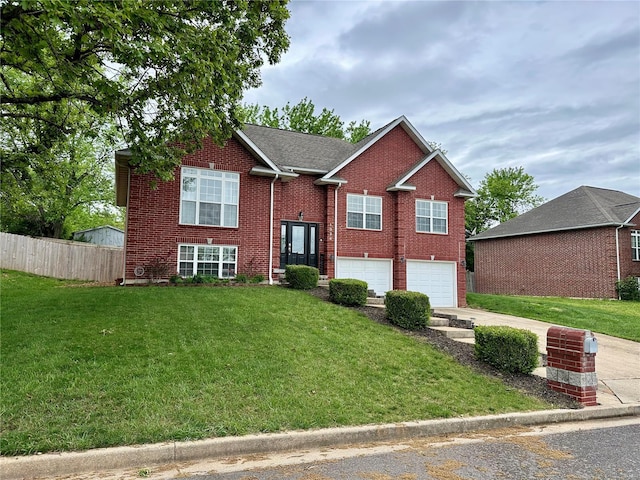 raised ranch with brick siding, fence, an attached garage, concrete driveway, and a front yard